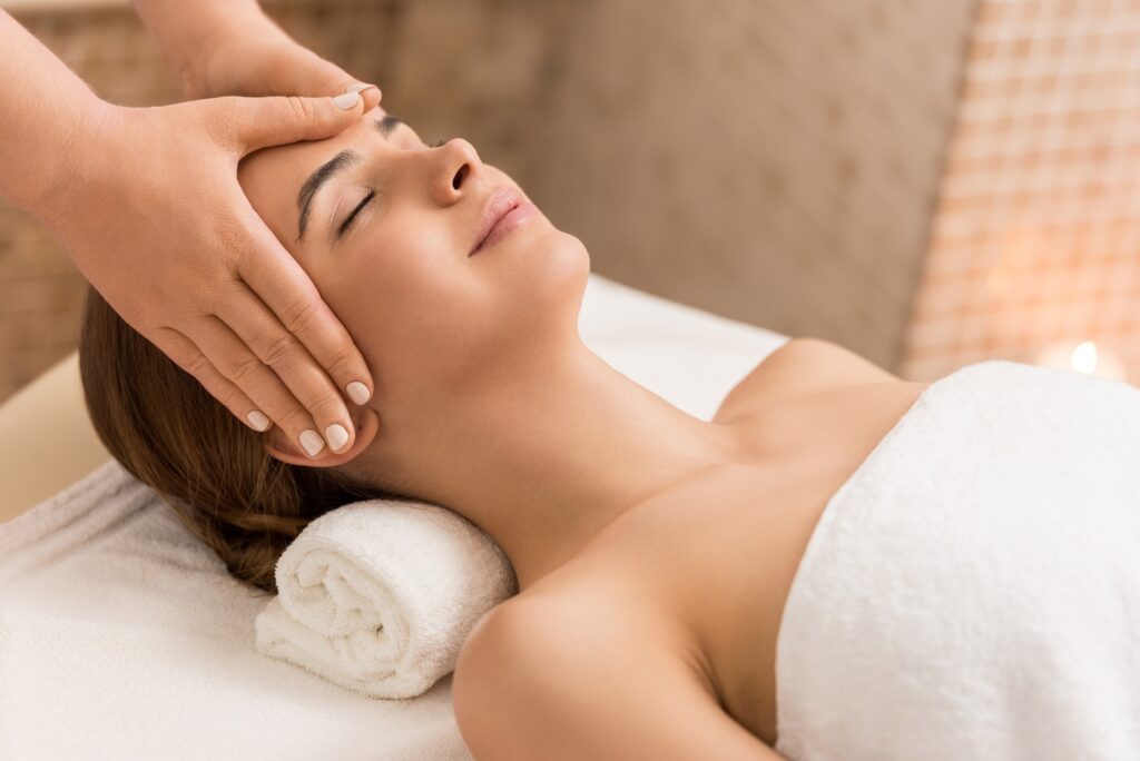 attractive woman relaxing and having head massage in massage salon