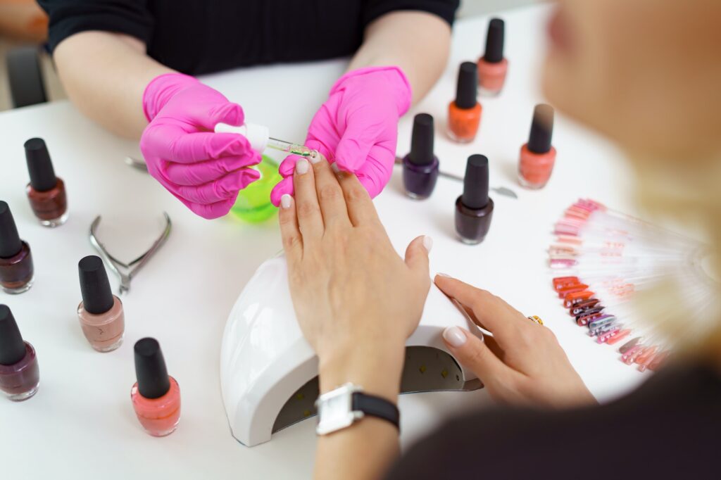 Manicurist treating client at beauty nails salon. Manicure, painting on nail